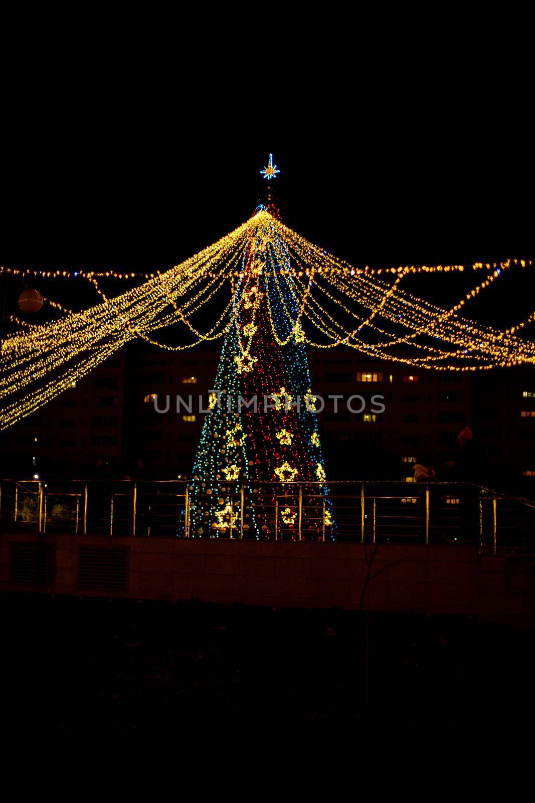 Long exposure night shot of a uniquely decorated main Christmas tree in the square after rain with reflection. by Matiunina