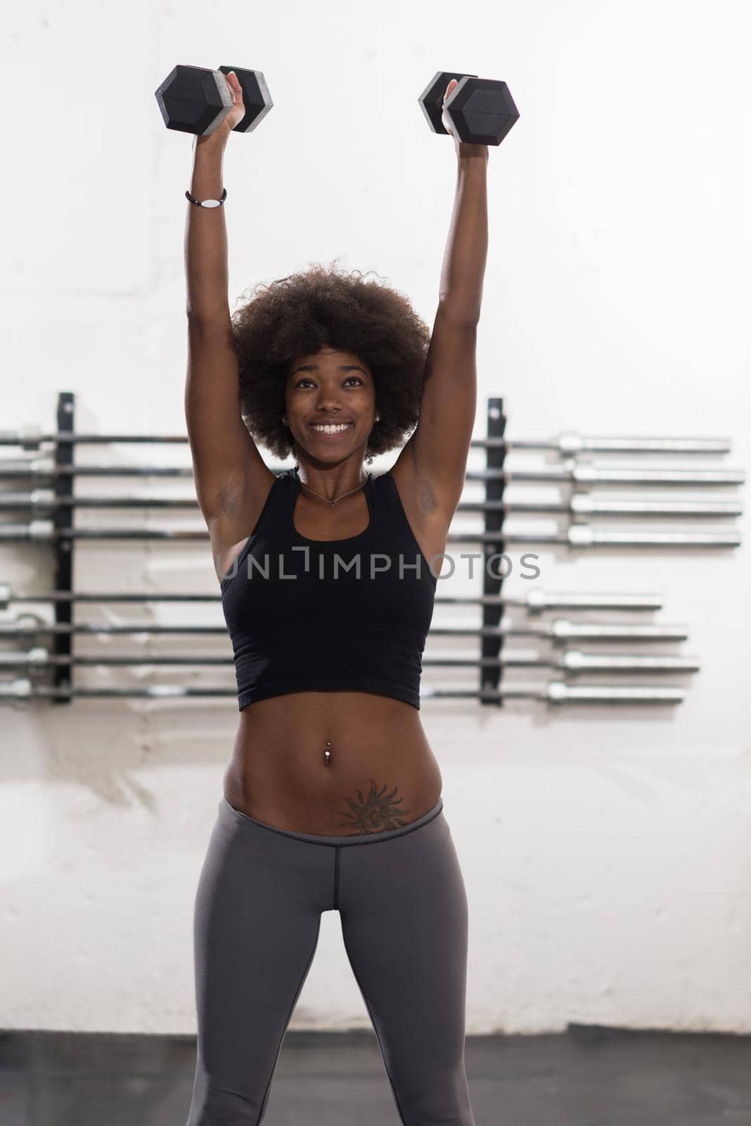 young beautiful African American woman doing bicep curls in a gym