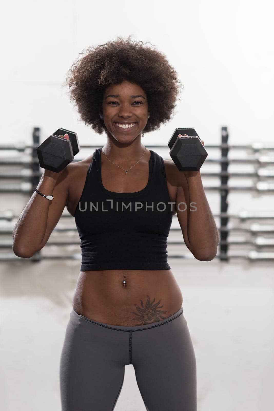 young beautiful African American woman doing bicep curls in a gym