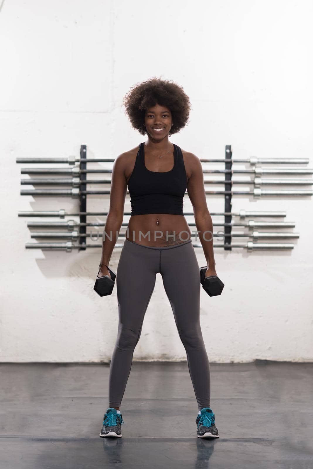 young beautiful African American woman doing bicep curls in a gym