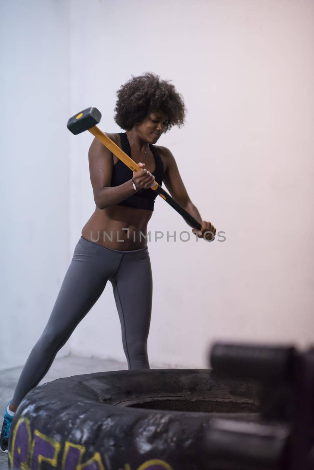 black woman workout with hammer and tractor tire by dotshock