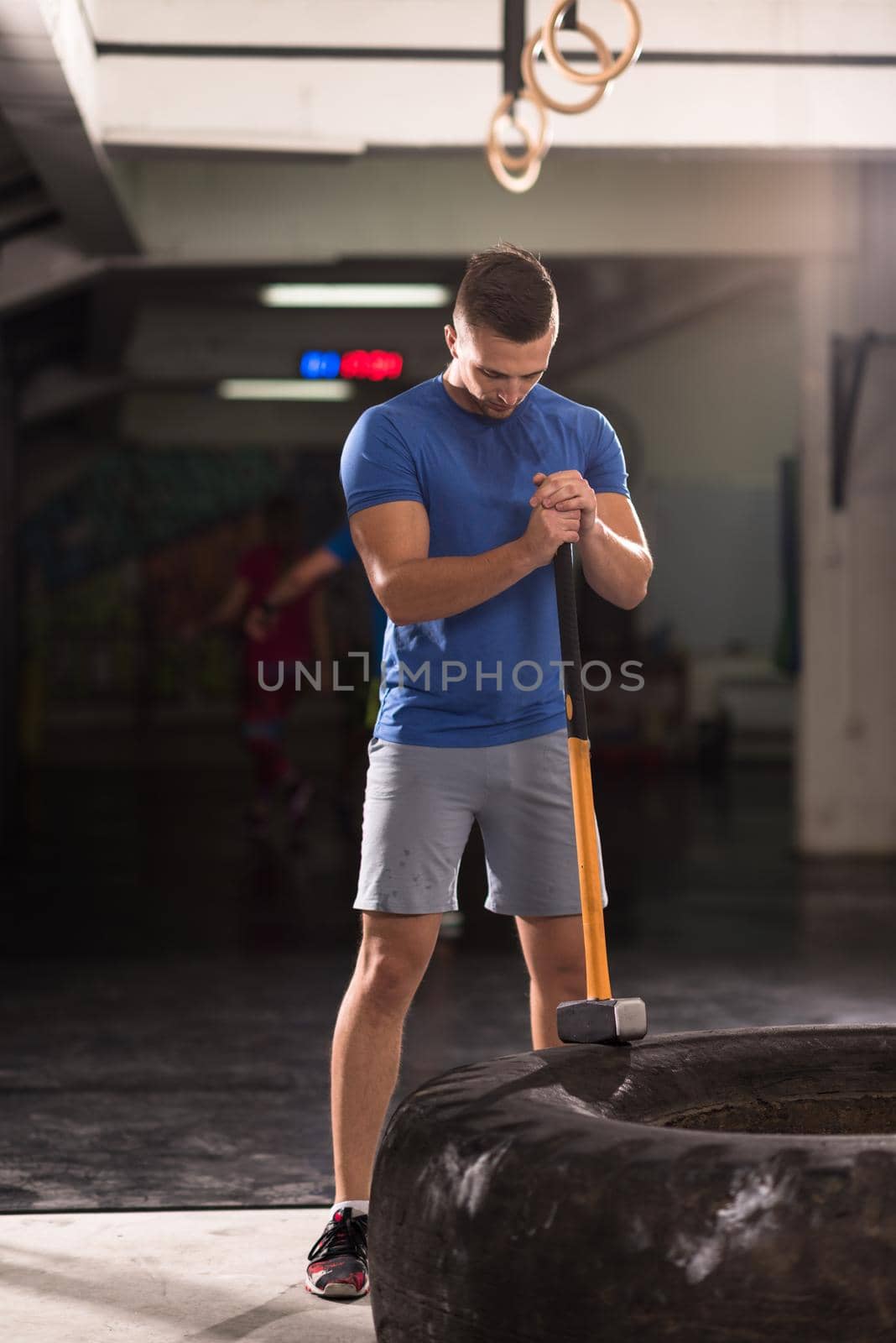 Sledgehammer Tire Hits young muscular man workout at gym with hammer and tractor tire