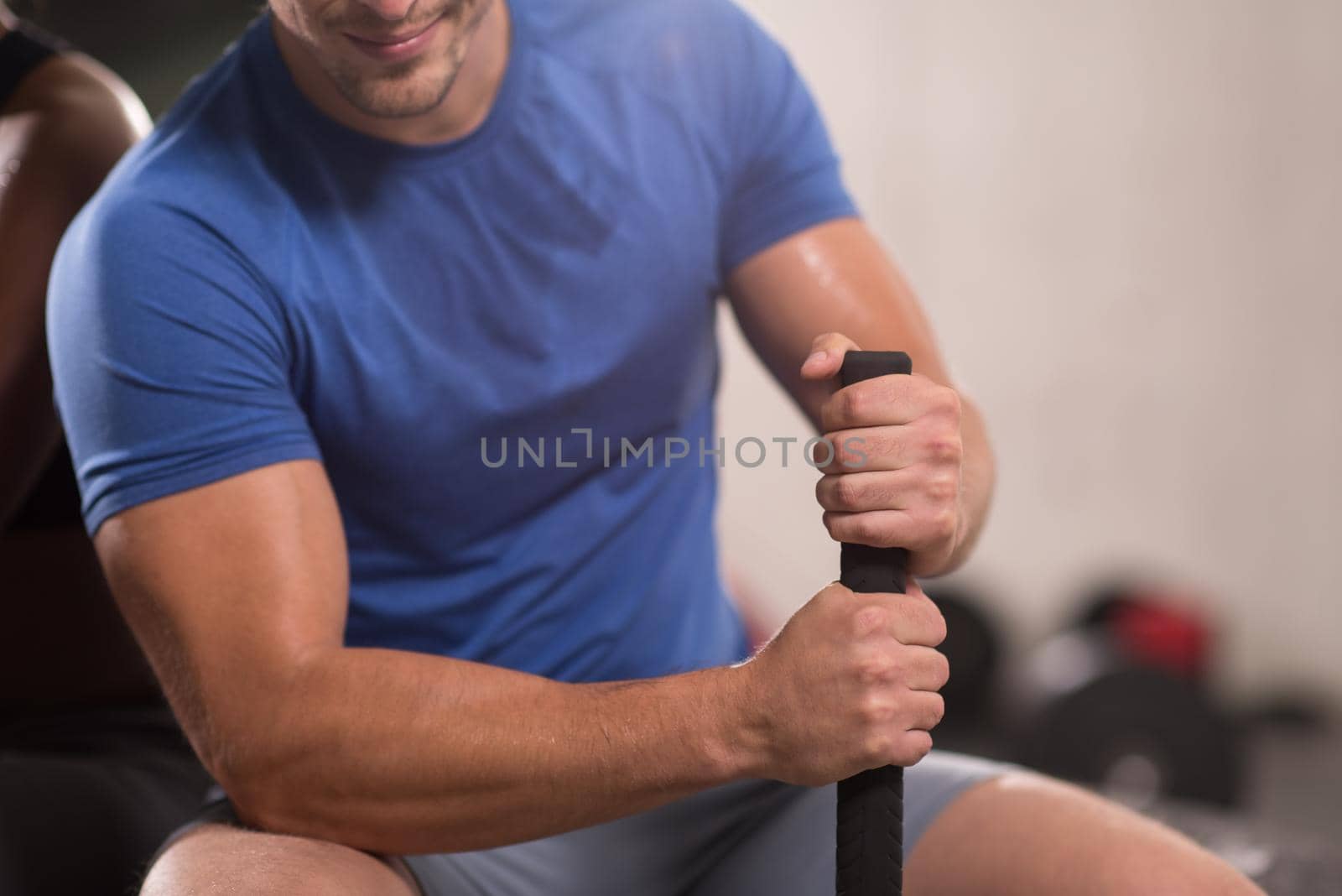 young muscular man after workout at gym with hammer and tractor tire with a focus on hands