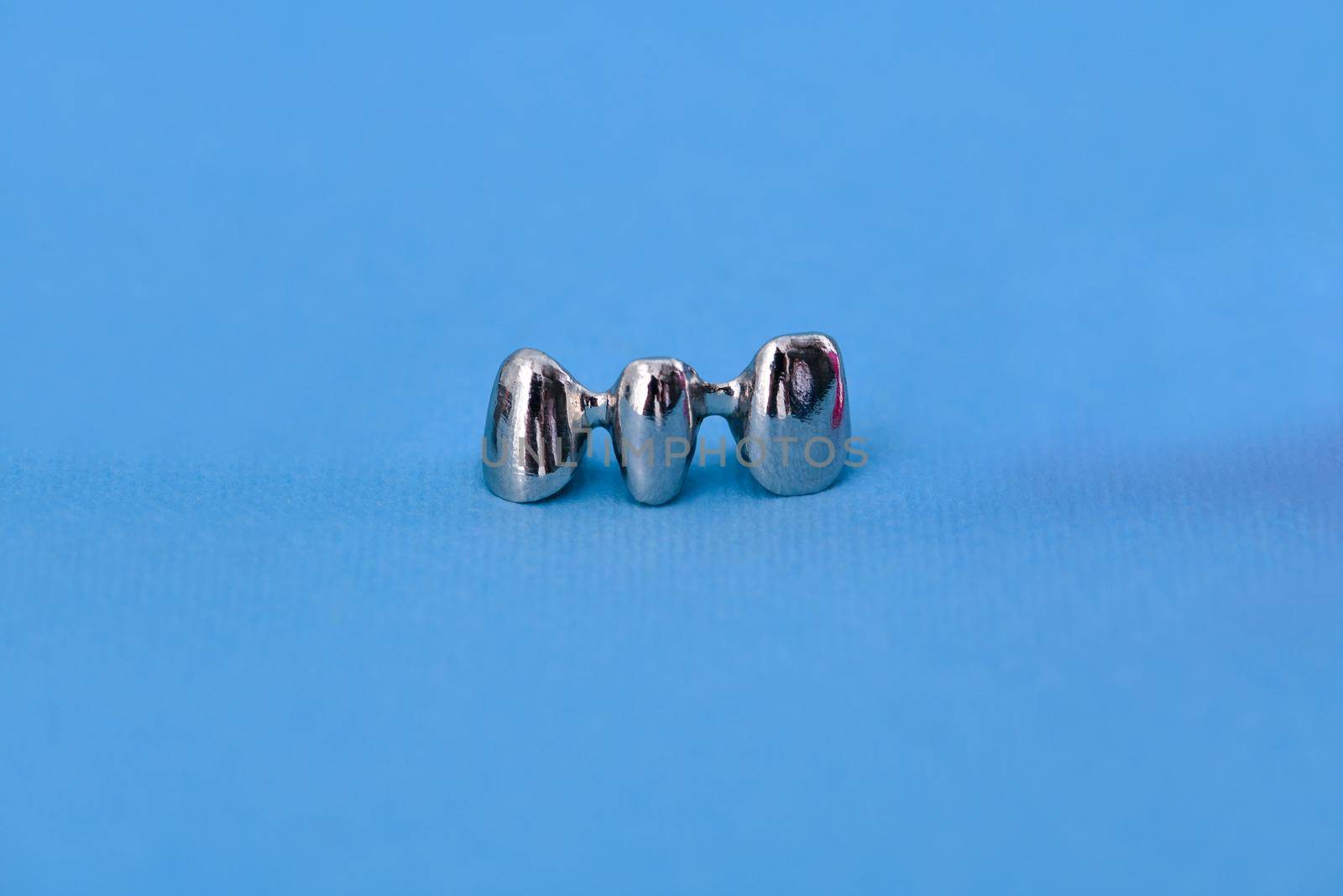 Dental silver metal tooth crowns isolated on blue background