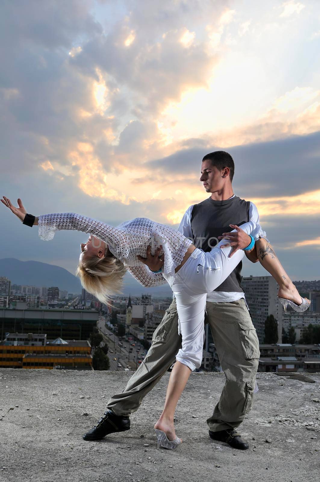 romantic urban couple dancing on top of the bulding 