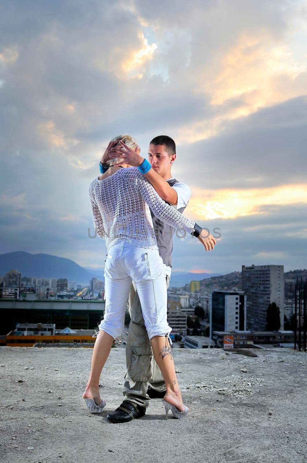 romantic urban couple dancing on top of  bulding by dotshock