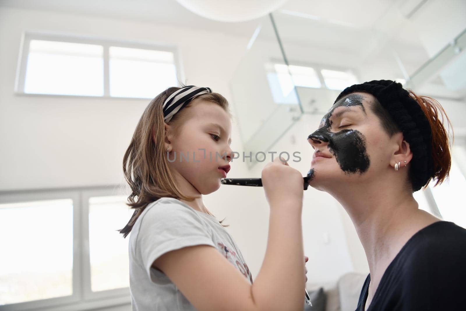 mother and daughter at home making facial mask beauty treatment by dotshock