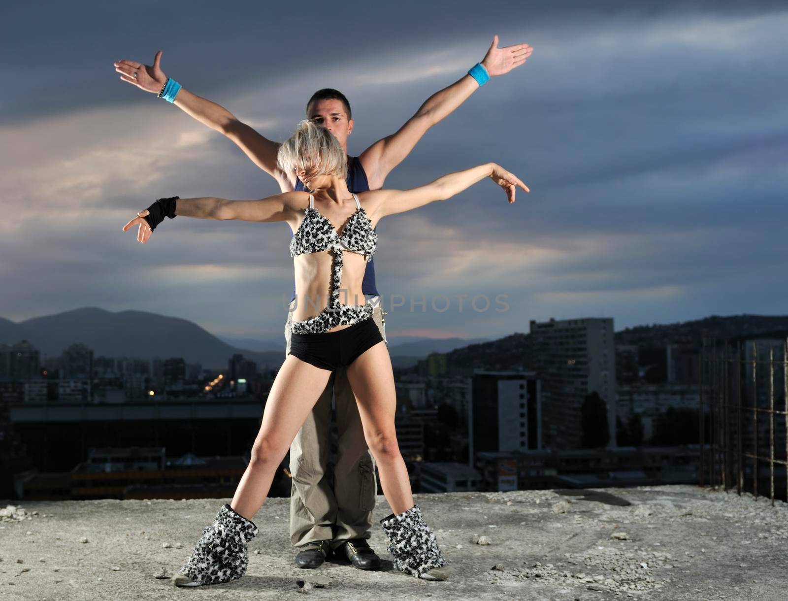 romantic urban couple dancing on top of the bulding at night scene