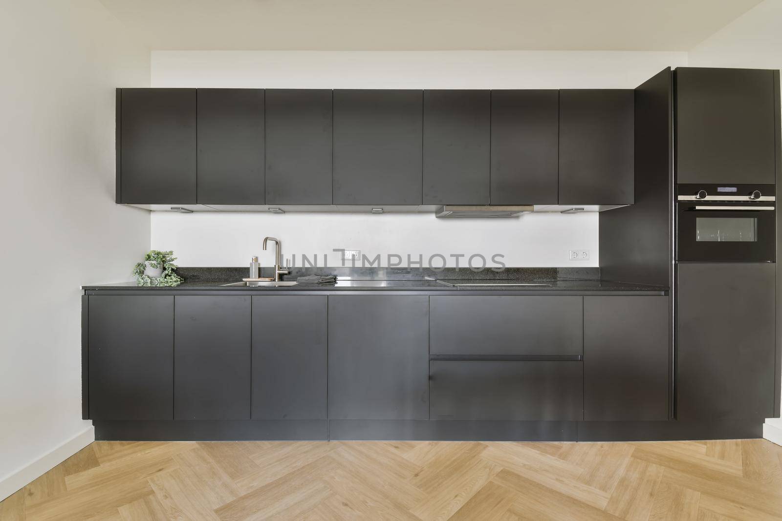 Black all-wall kitchen set in modern kitchen with parquet floor