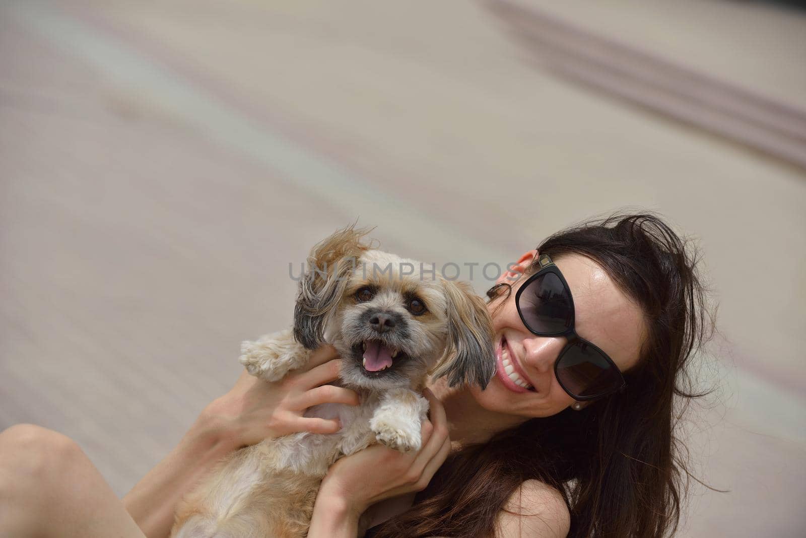 beautiful happy young  woman in black dress with cute small dog puppy have fun on street