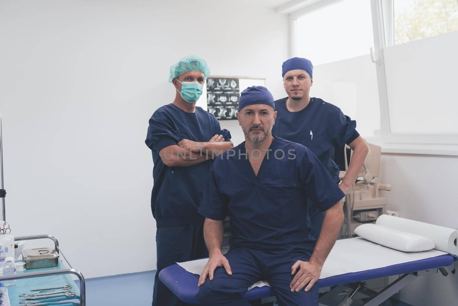 Multiethnic orthopedic doctor in front of his medical team looking at camera wearing face mask  by dotshock