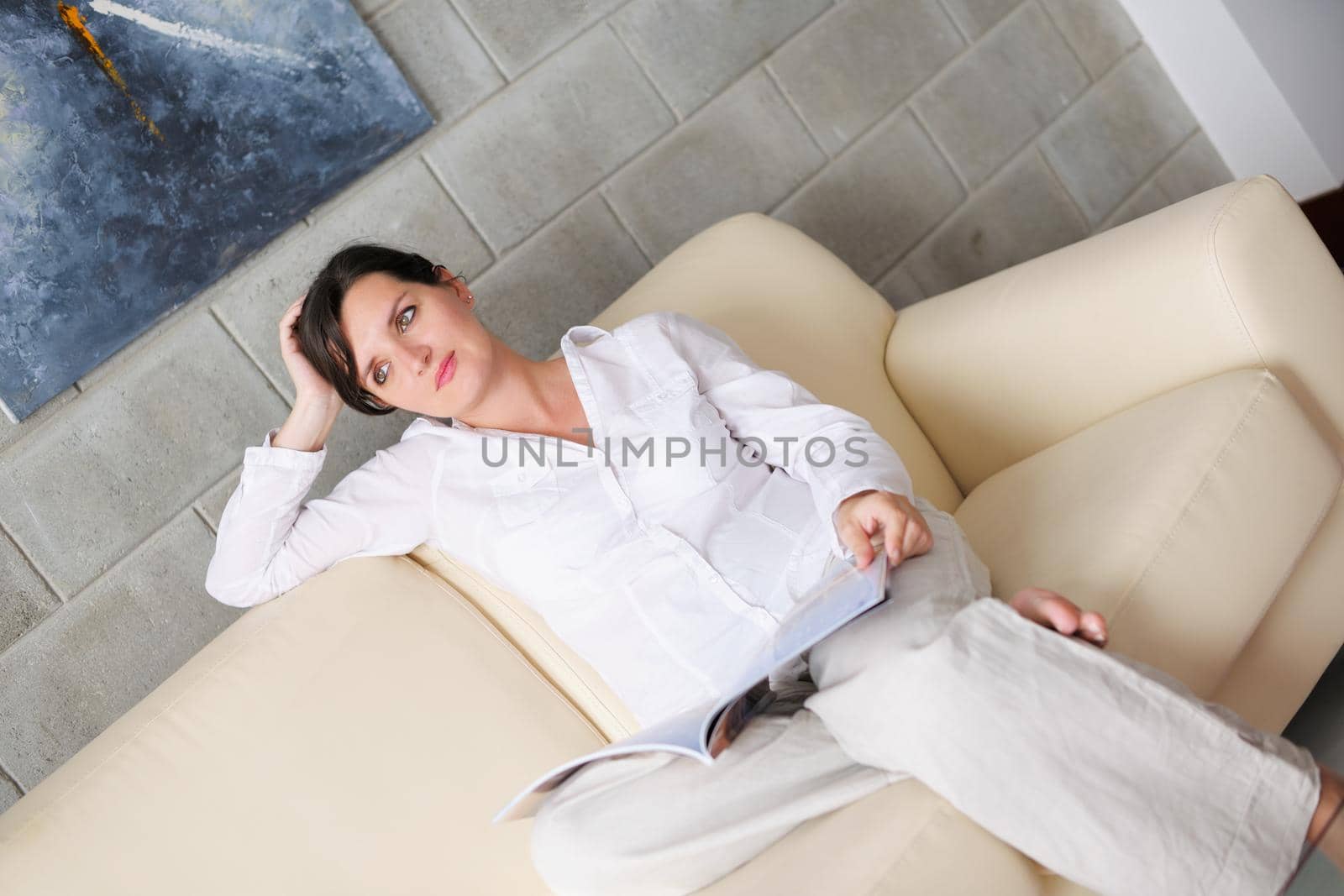 happpy young woman reading magazina at home in comfortabel sofa and bright living room