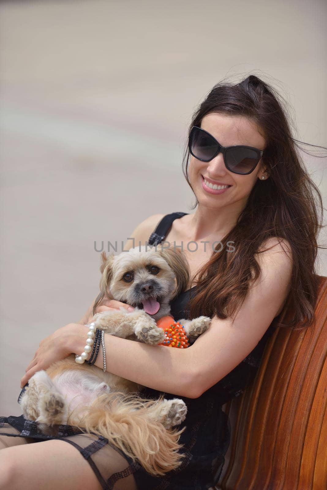 beautiful happy young  woman in black dress with cute small dog puppy have fun on street