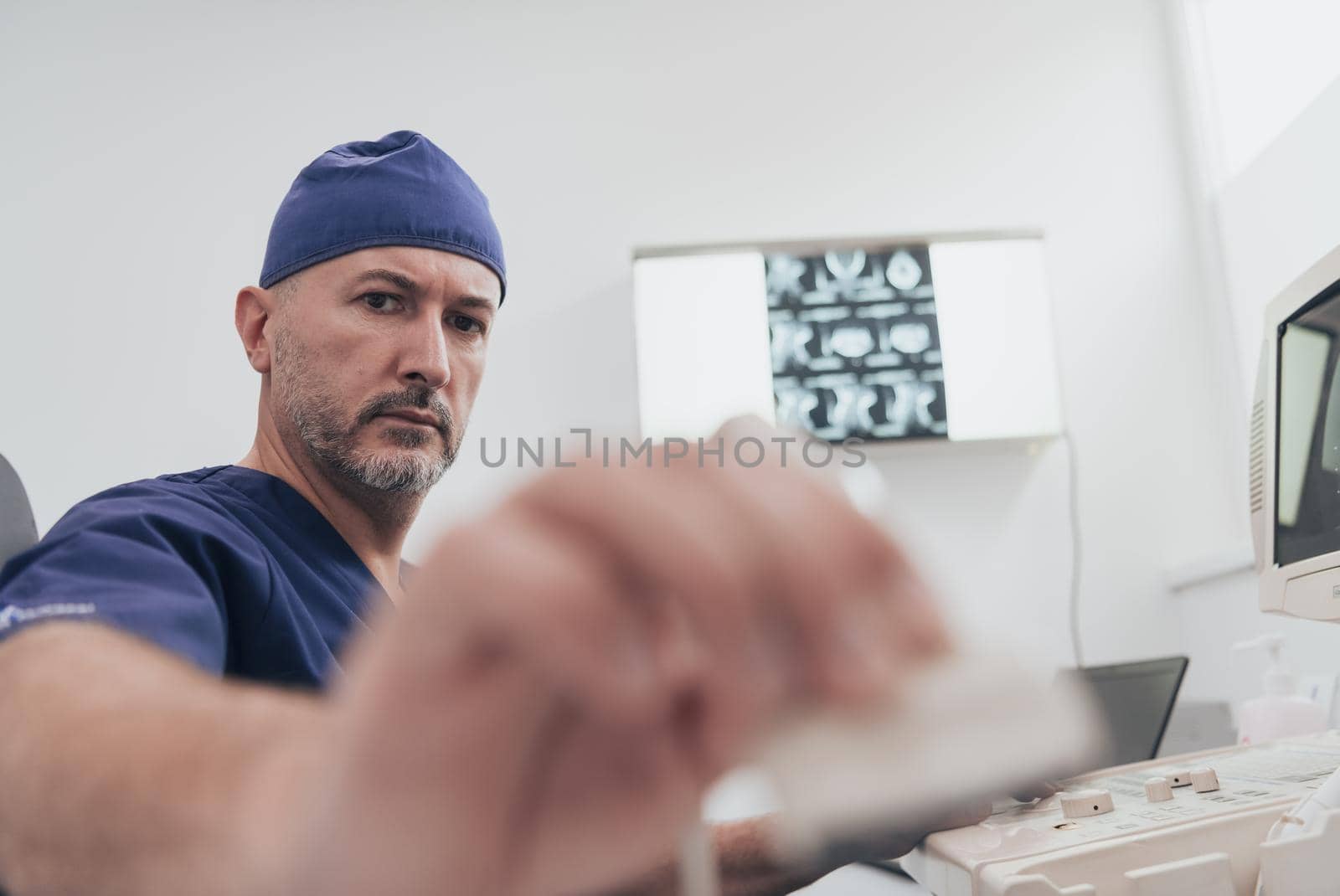 Mature male orthopedist doctor working at the hospital operating ultrasound scanning machine examining knee of her female patient technology modern or medicine people vitality concept. Selective focus