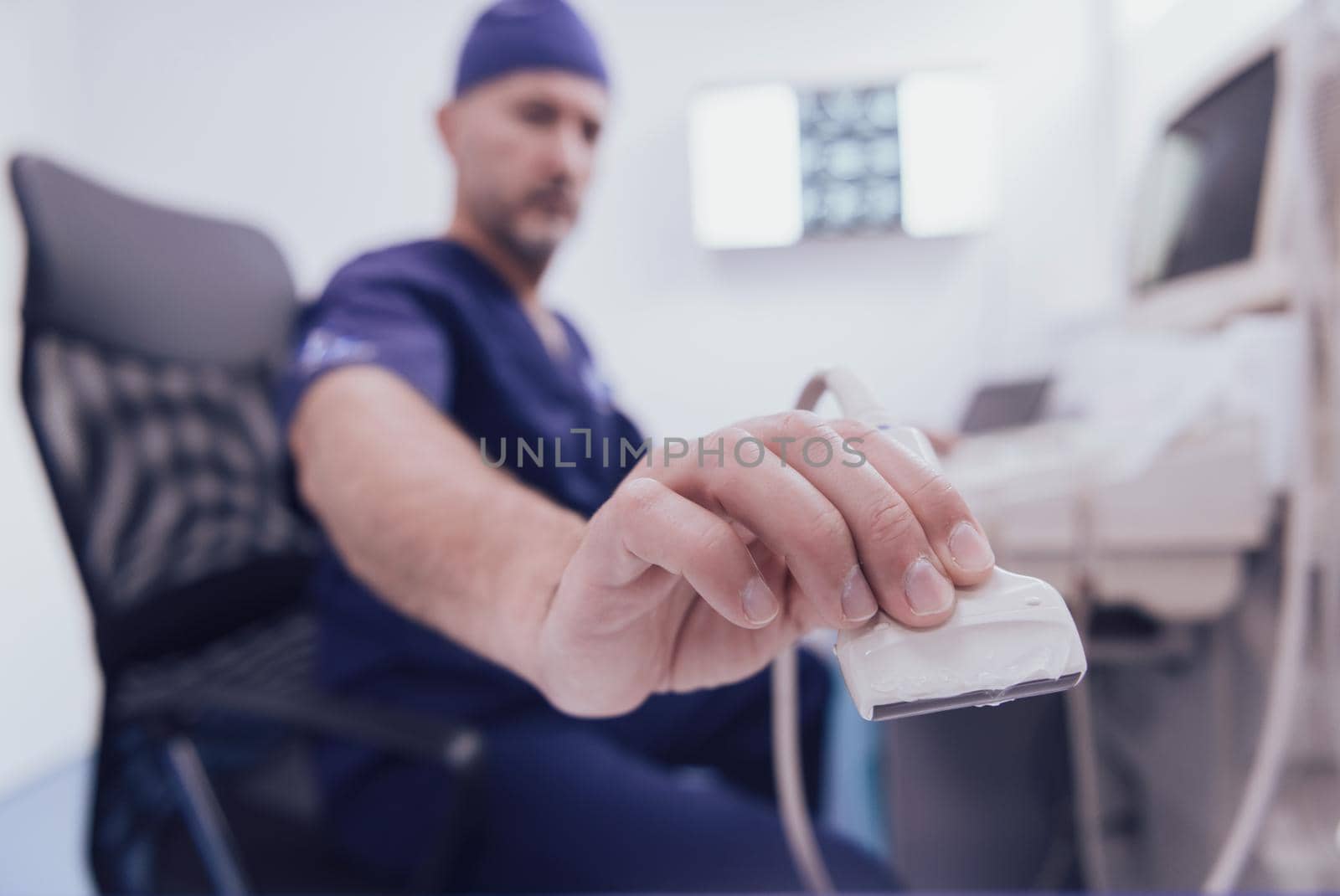 Mature male orthopedist doctor working at the hospital operating ultrasound scanning machine examining knee of her female patient technology modern or medicine people vitality concept. Selective focus