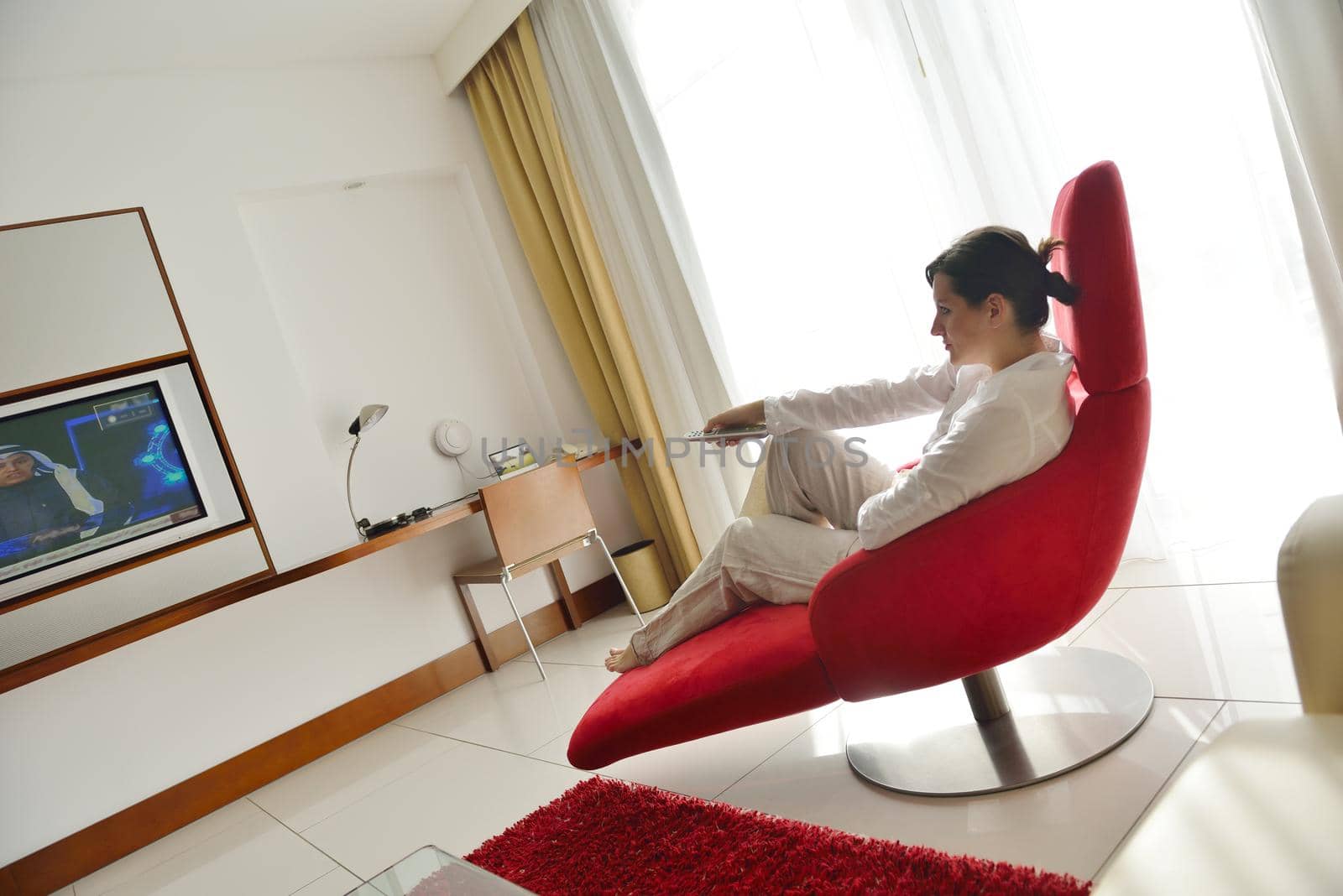 happy young woman relax at home on sofa in bright living room and watching tv