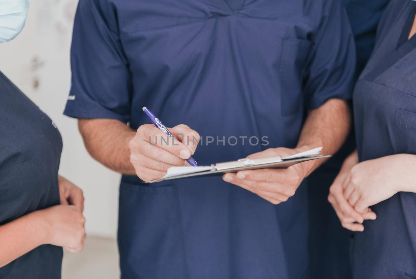 Orthopedic doctor in front of his medical multiethnic team wearing a face mask during covid-19 outbreak. Surgeon in front of his colleagues. Selective focus.