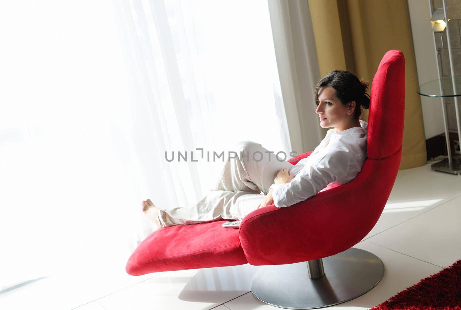 happy young woman relax at home on sofa in bright living room and watching tv