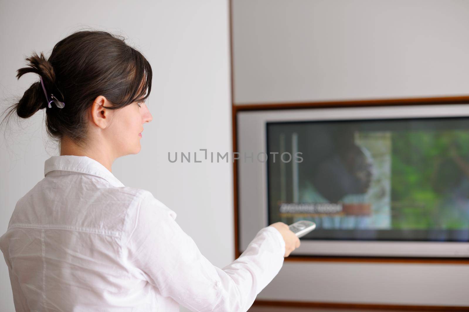 happy young woman watching tv at modern home livingroom