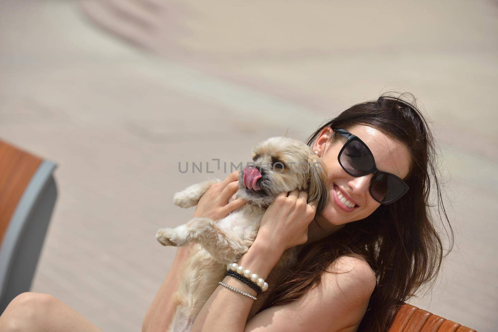 beautiful happy young  woman in black dress with cute small dog puppy have fun on street