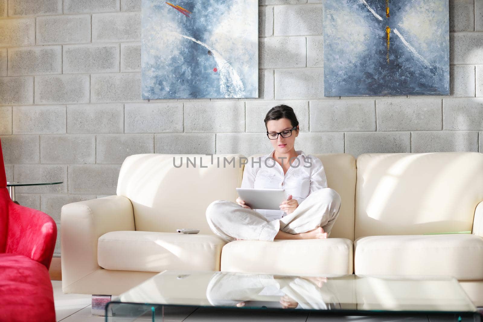 Young woman at home relaxing in her lliving room reading a digital tablet PC surf internet and work