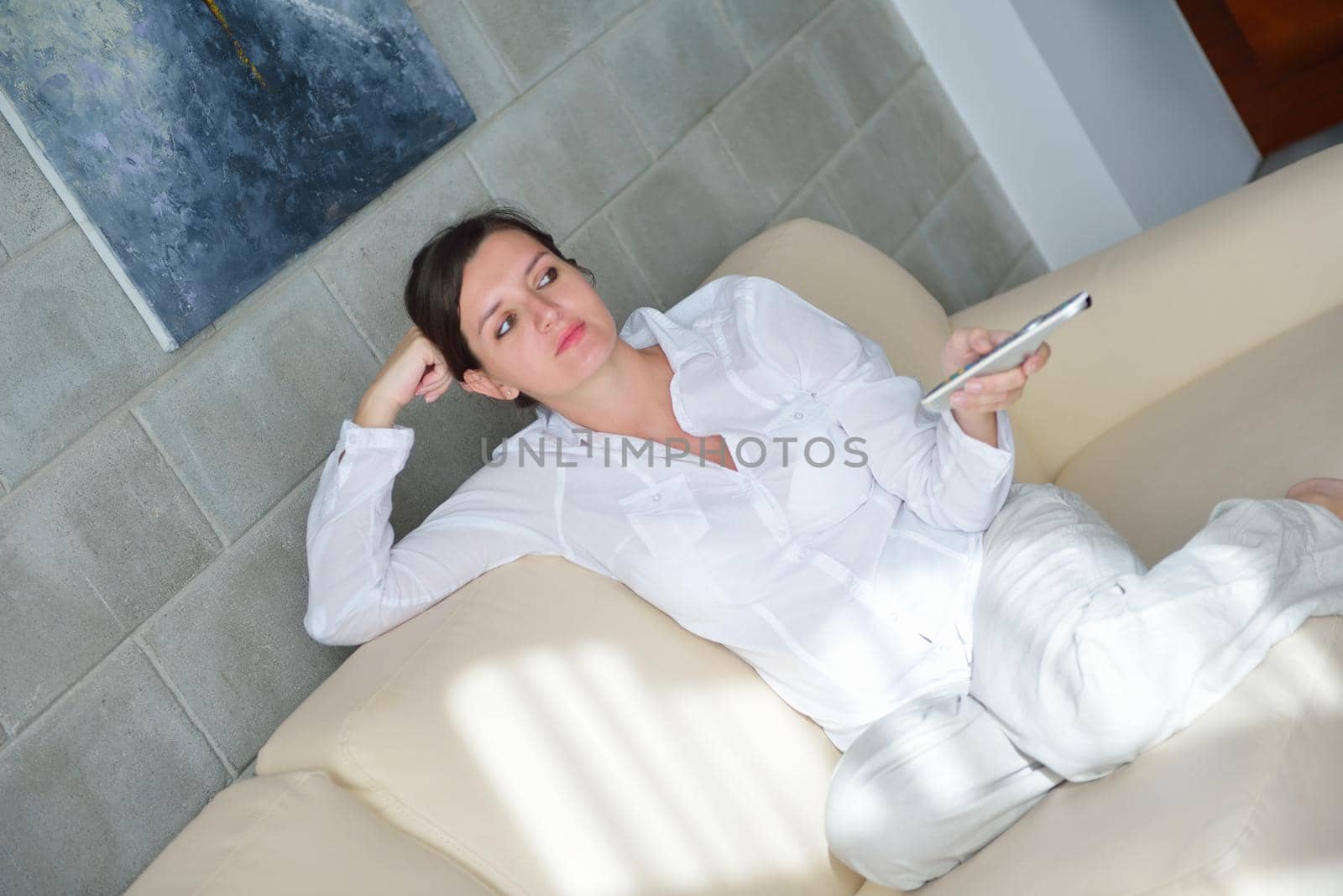 happy young woman relax at home on sofa in bright living room and watching tv