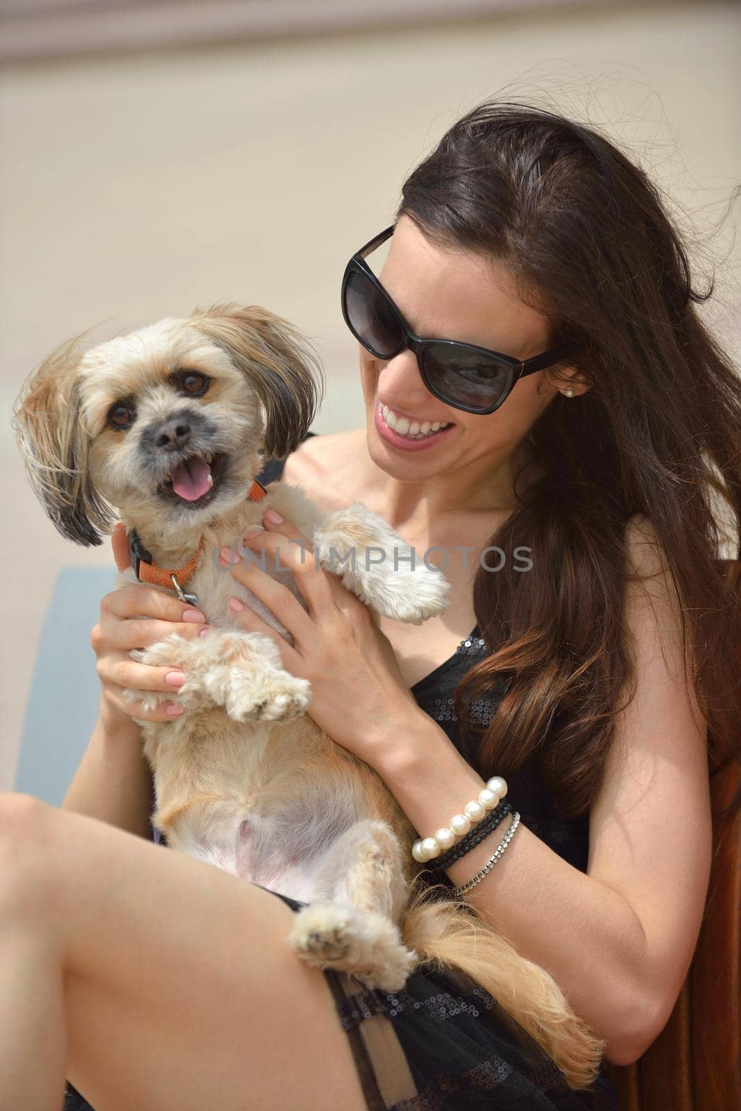 beautiful happy young  woman in black dress with cute small dog puppy have fun on street