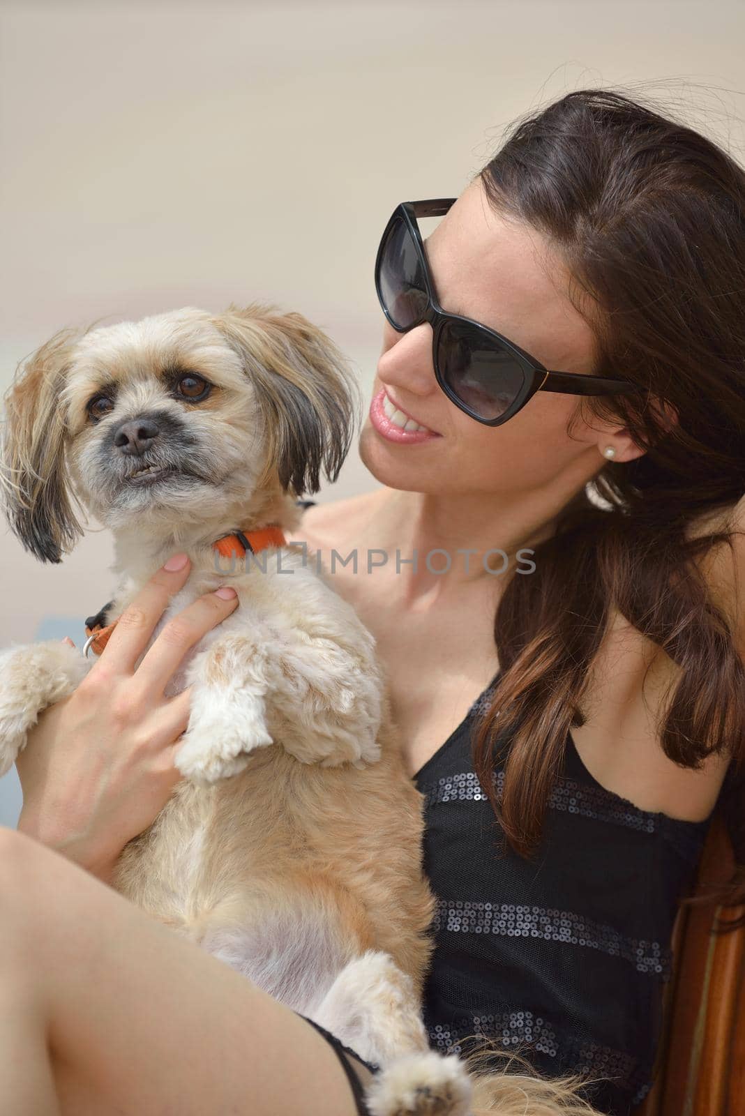 beautiful happy young  woman in black dress with cute small dog puppy have fun on street