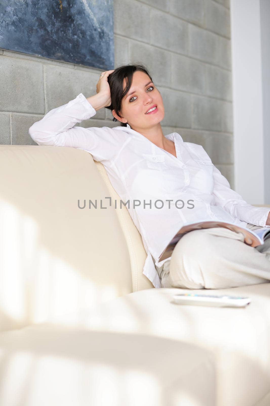 happpy young woman reading magazina at home in comfortabel sofa and bright living room