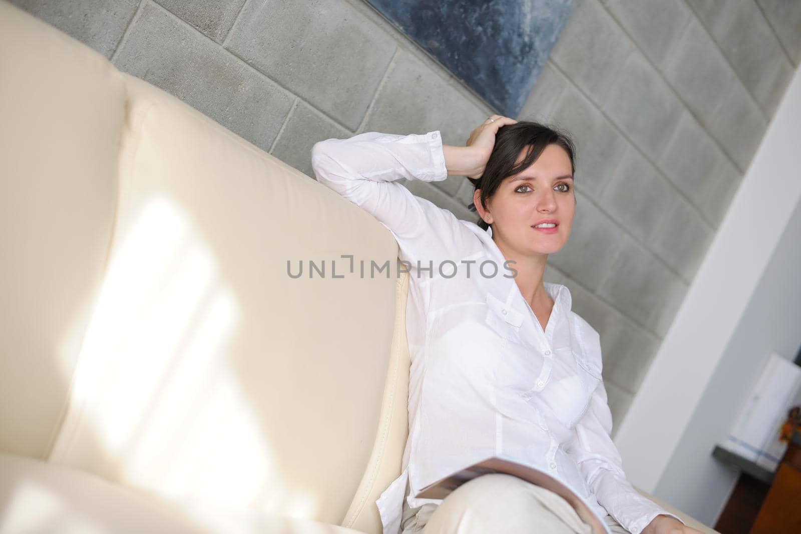 happpy young woman reading magazina at home in comfortabel sofa and bright living room