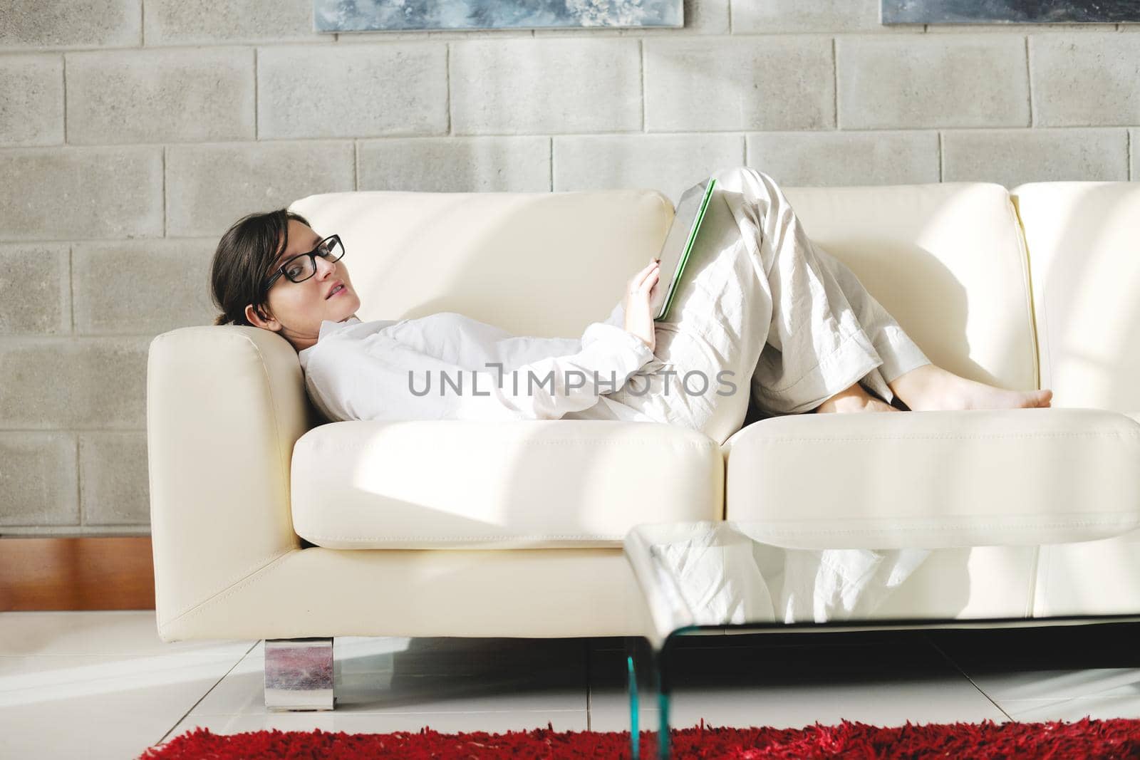 Young woman at home relaxing in her lliving room reading a digital tablet PC surf internet and work