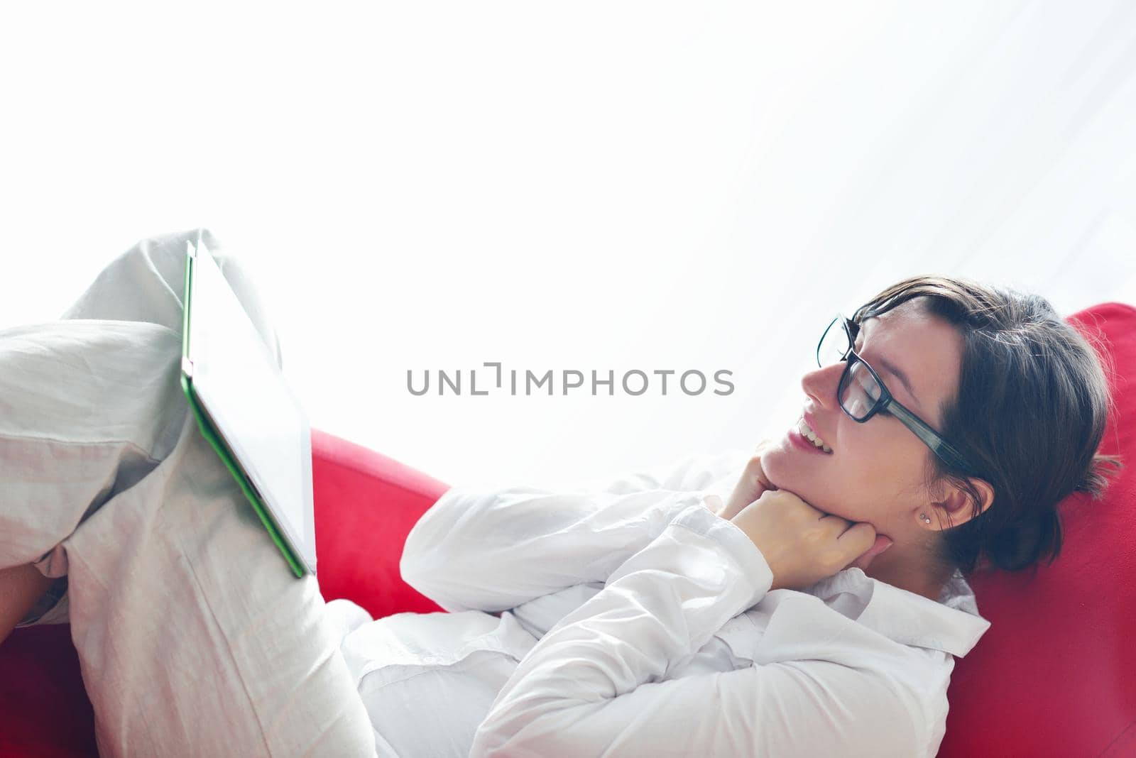 Young woman at home relaxing in her lliving room reading a digital tablet PC surf internet and work