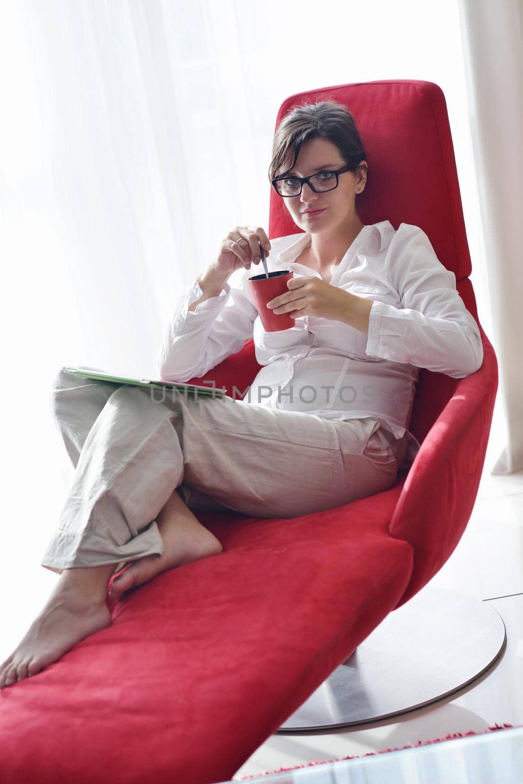 Young woman at home relaxing in her lliving room reading a digital tablet PC surf internet and work