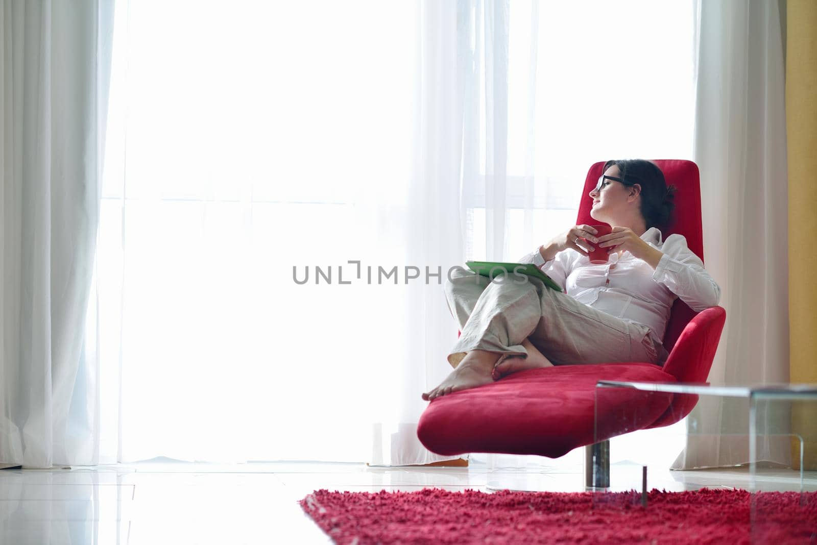 Young woman at home relaxing in her lliving room reading a digital tablet PC surf internet and work