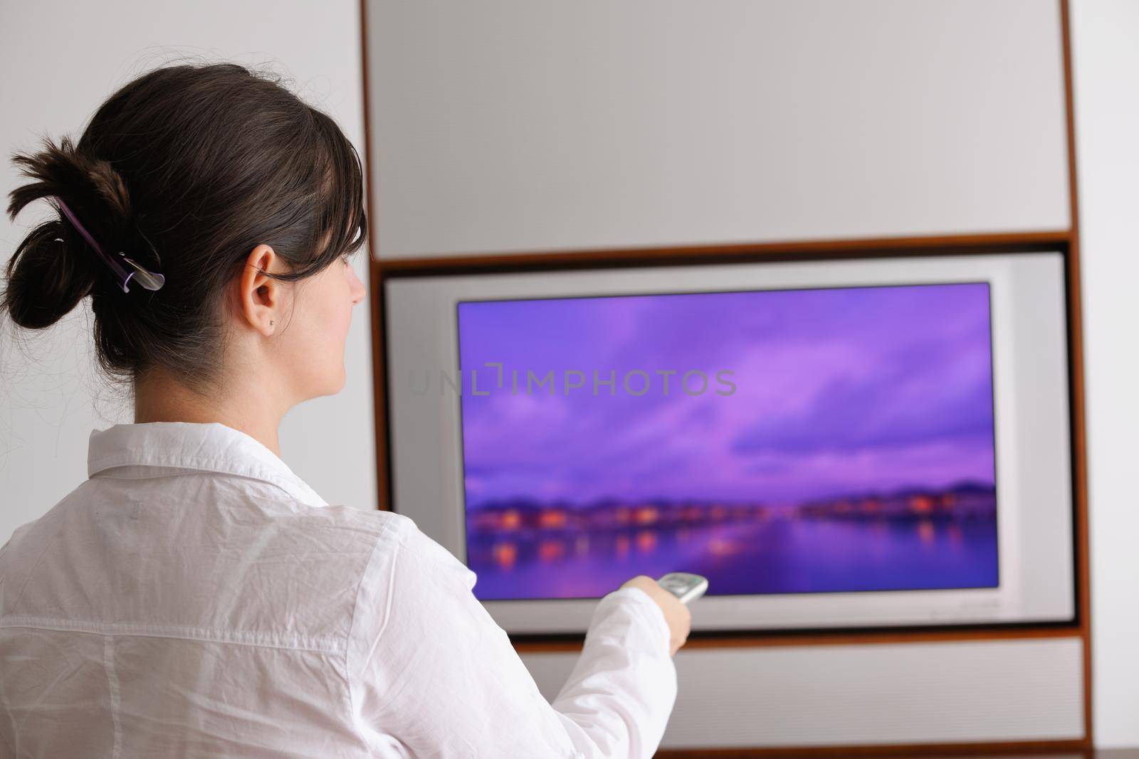 happy young woman watching tv at modern home livingroom