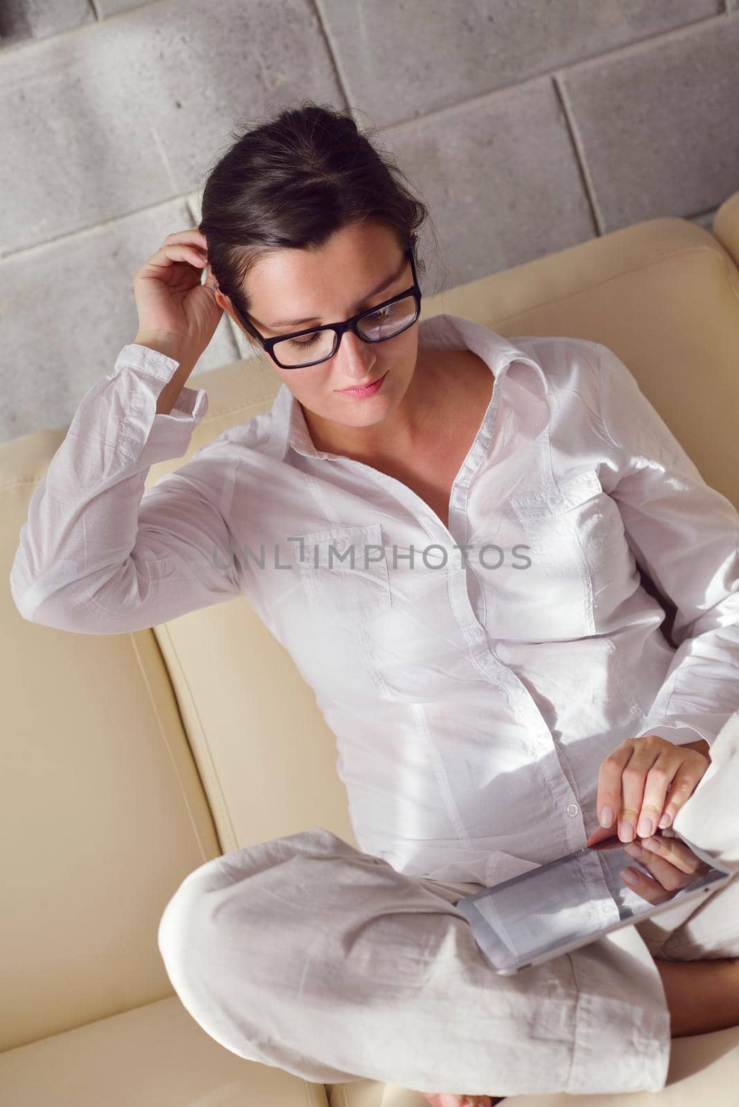 Young woman at home relaxing in her lliving room reading a digital tablet PC surf internet and work