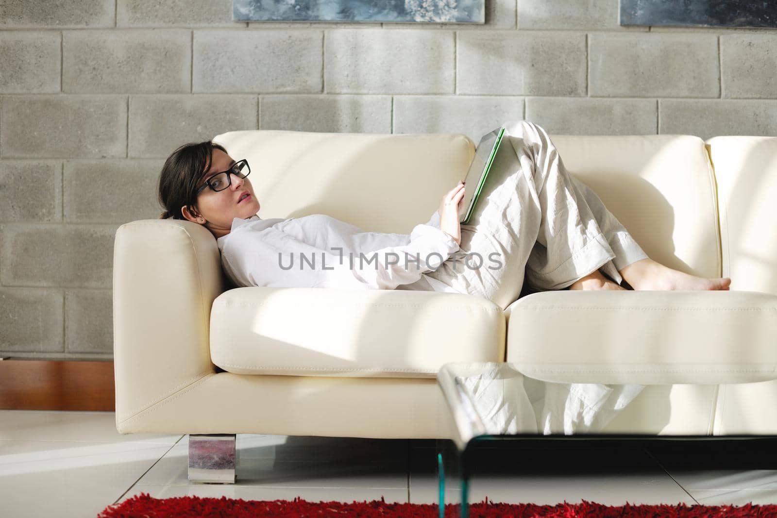 Young woman at home relaxing in her lliving room reading a digital tablet PC surf internet and work