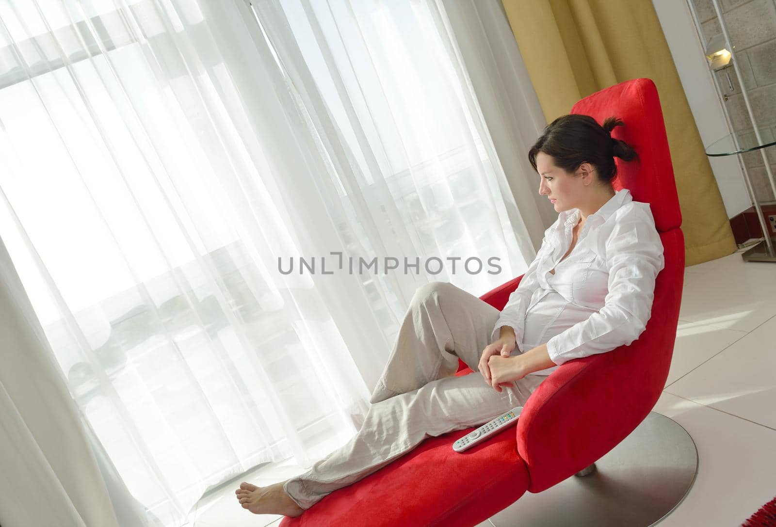 happy young woman relax at home on sofa in bright living room and watching tv