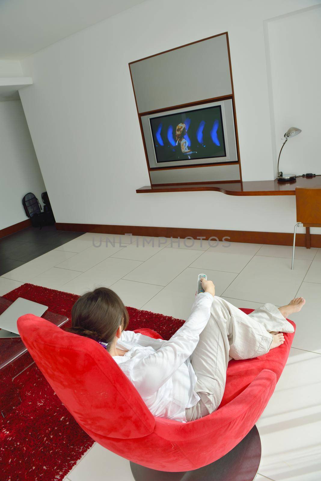 happy young woman watching tv at modern home livingroom