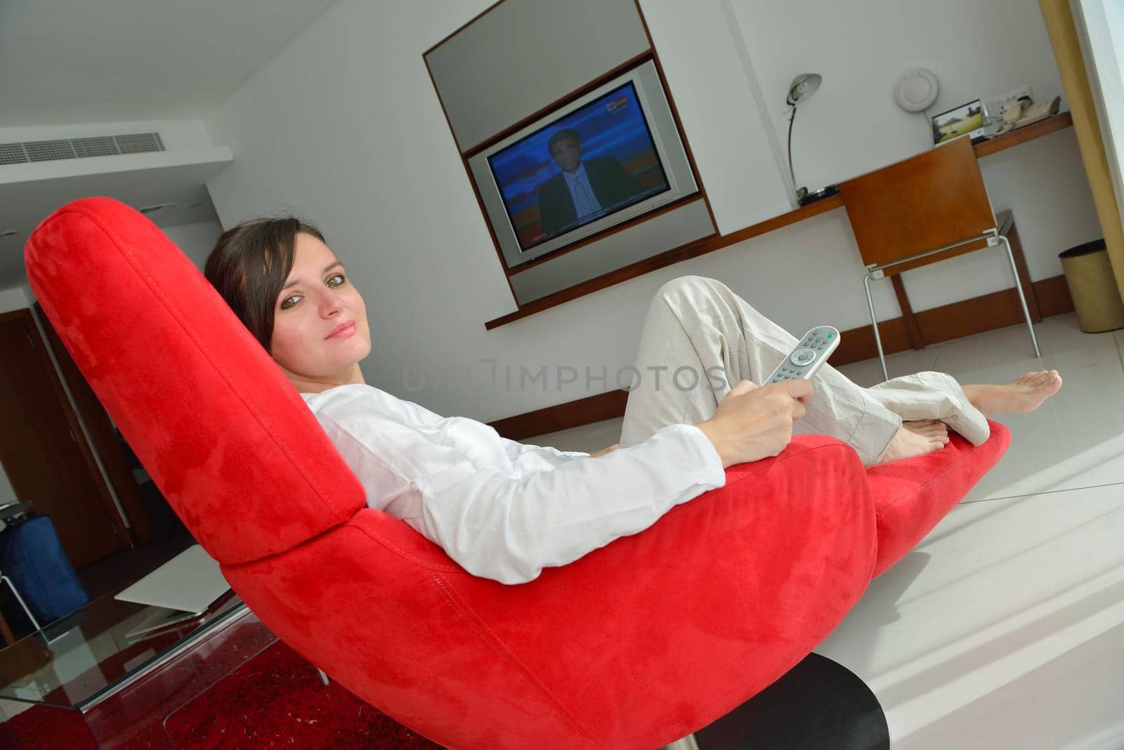 happy young woman relax at home on sofa in bright living room and watching tv