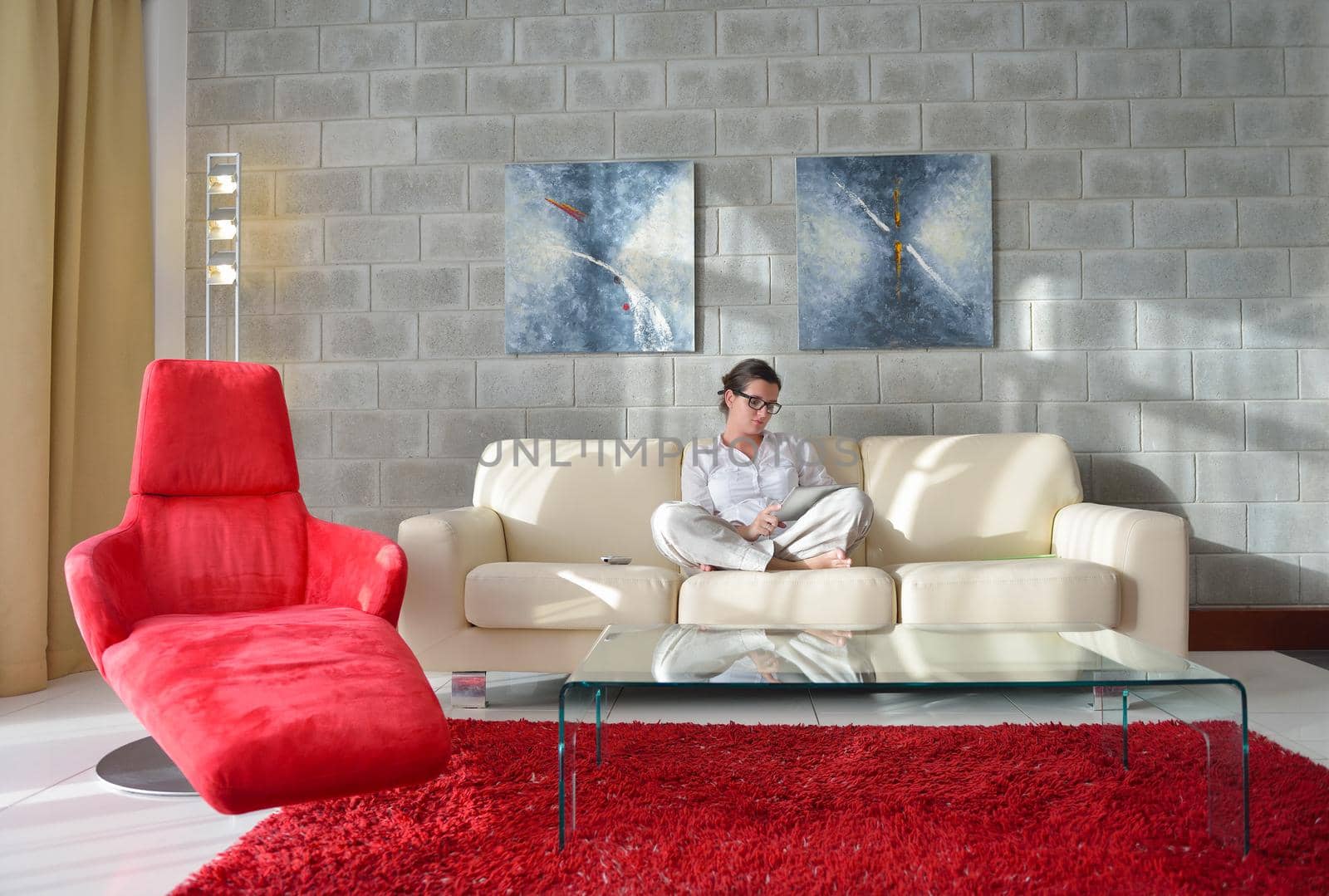 Young woman at home relaxing in her lliving room reading a digital tablet PC surf internet and work