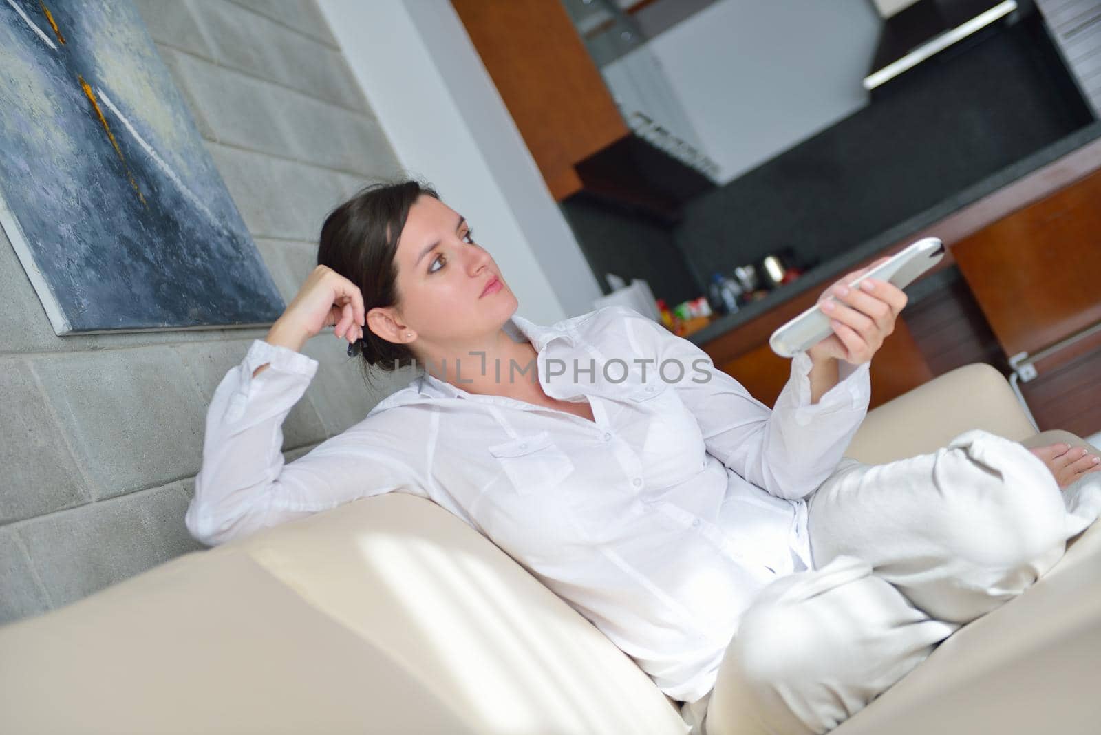 happy young woman relax at home on sofa in bright living room and watching tv