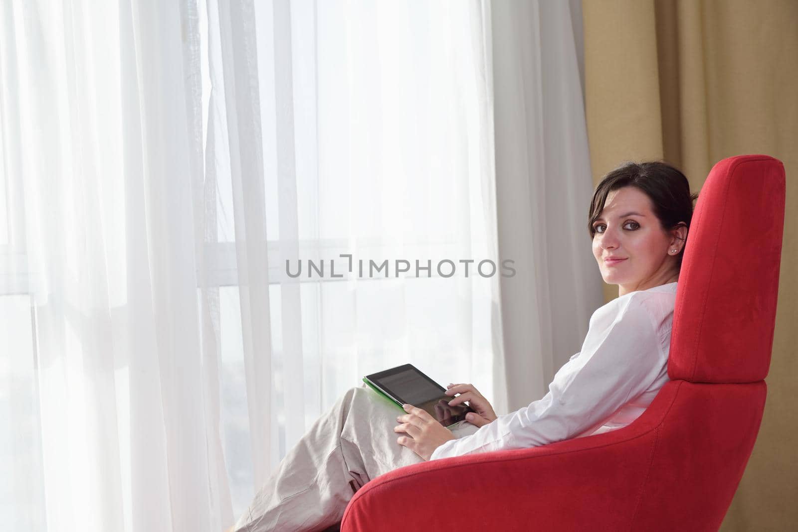 Young woman at home relaxing in her lliving room reading a digital tablet PC surf internet and work