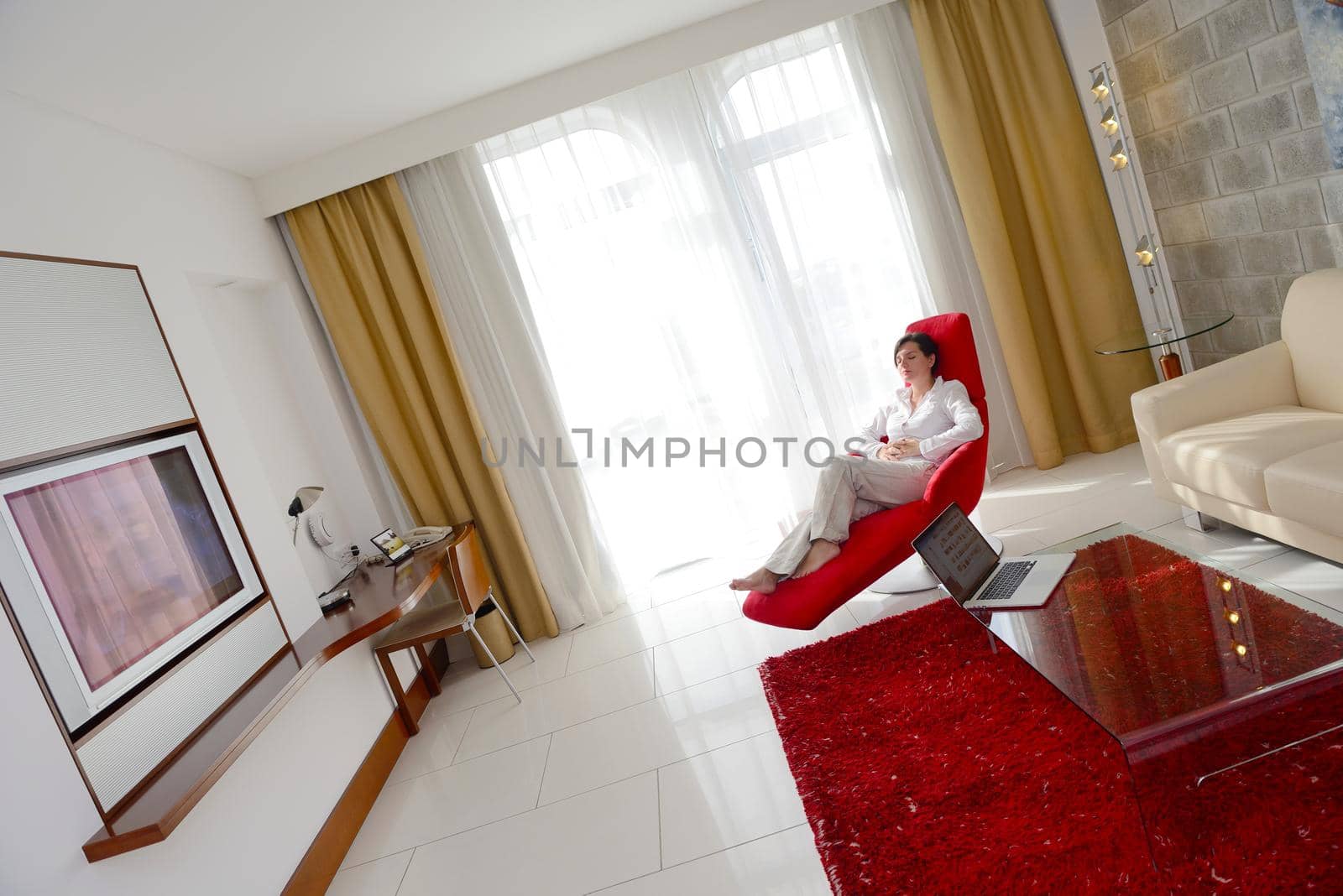 happy young woman relax at home on sofa in bright living room and watching tv