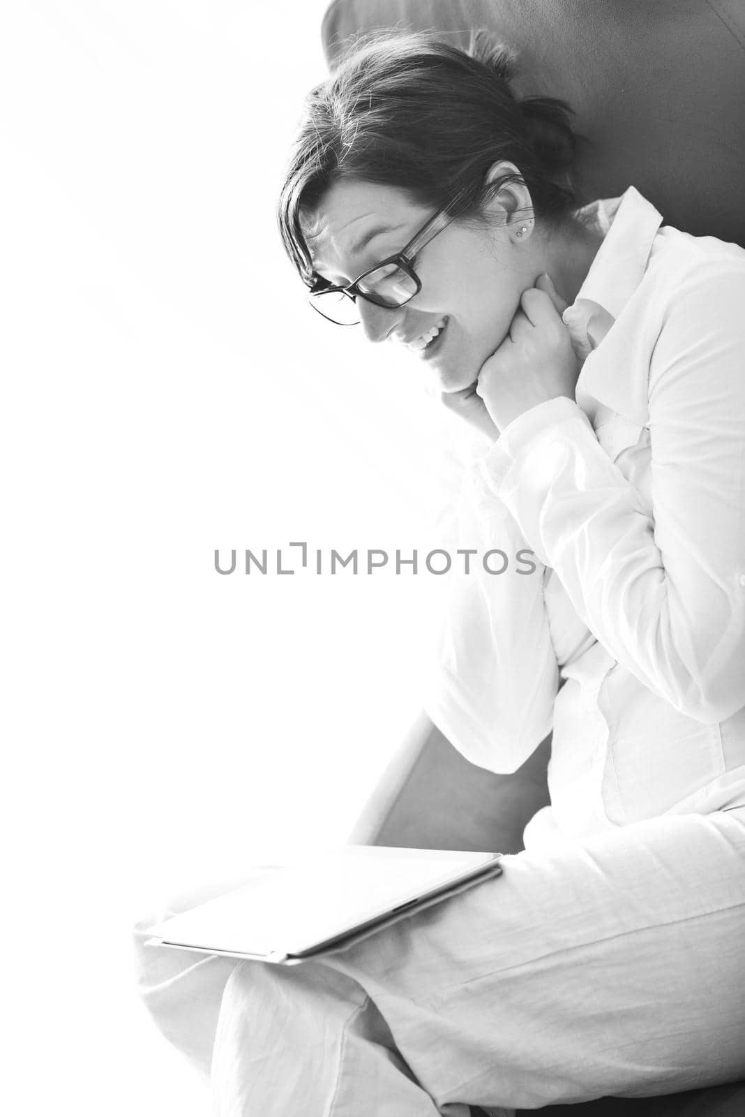 Young woman at home relaxing in her lliving room reading a digital tablet PC surf internet and work