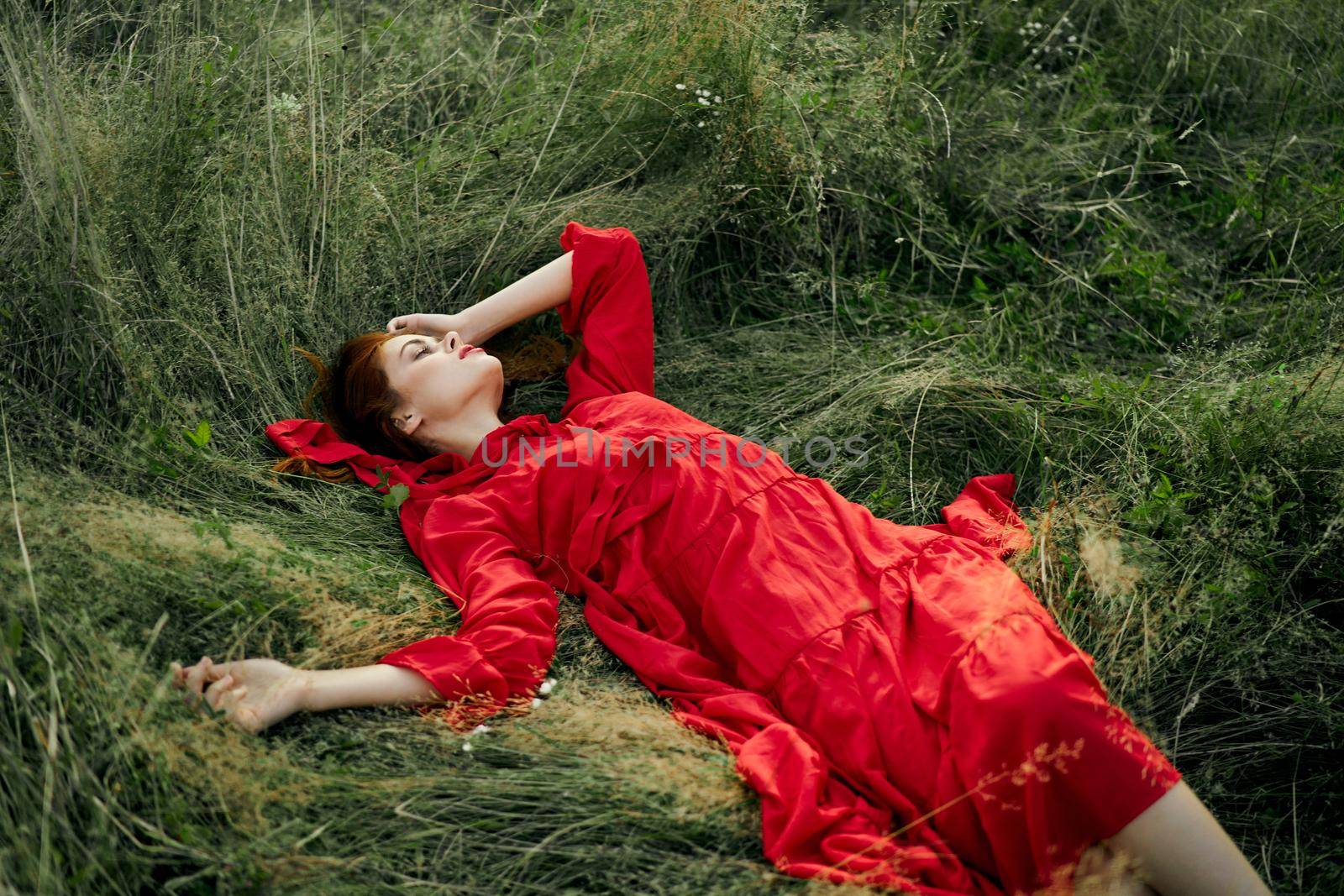 woman in red dress lies on the grass in the field nature landscape by Vichizh