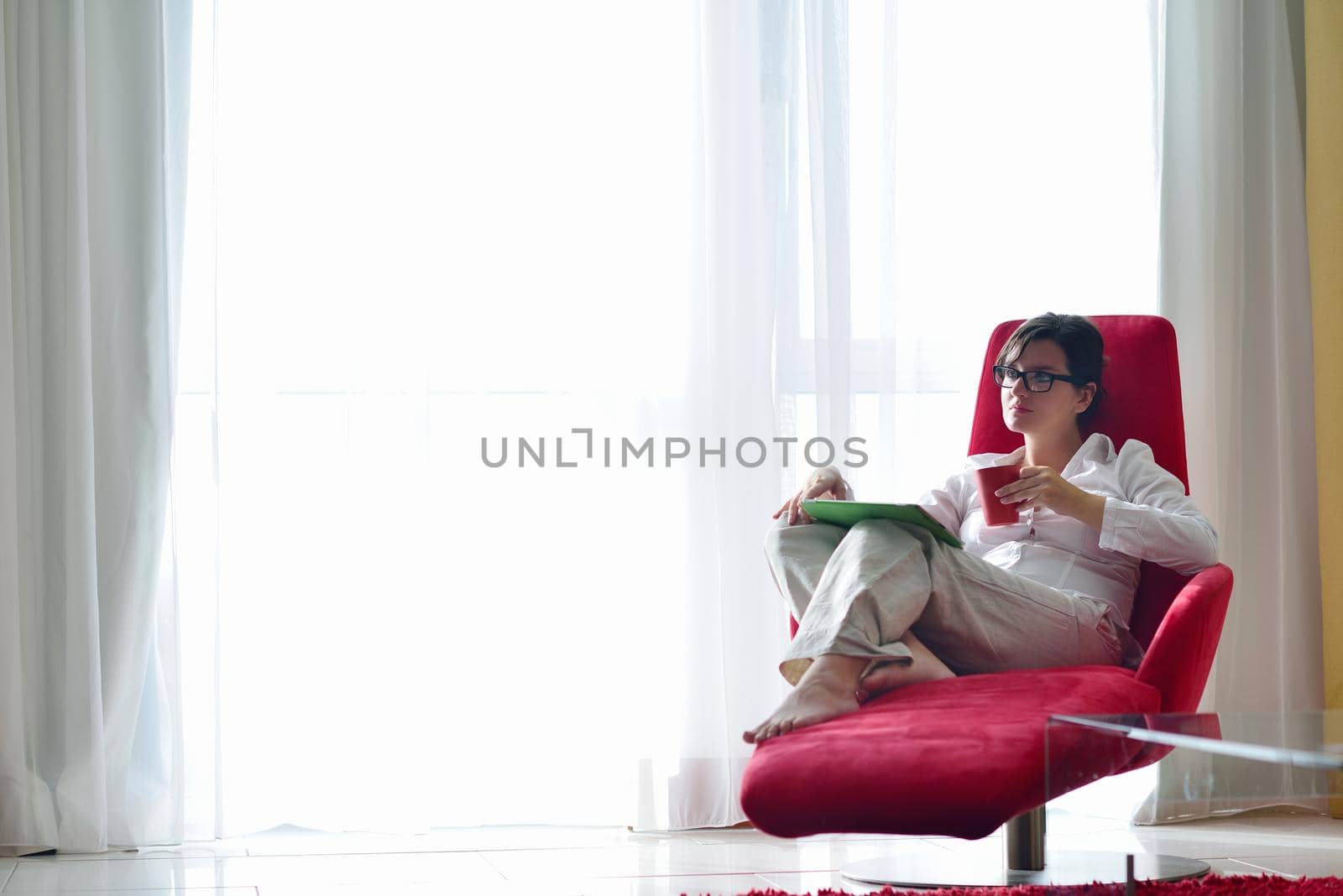 Young woman at home relaxing in her lliving room reading a digital tablet PC surf internet and work