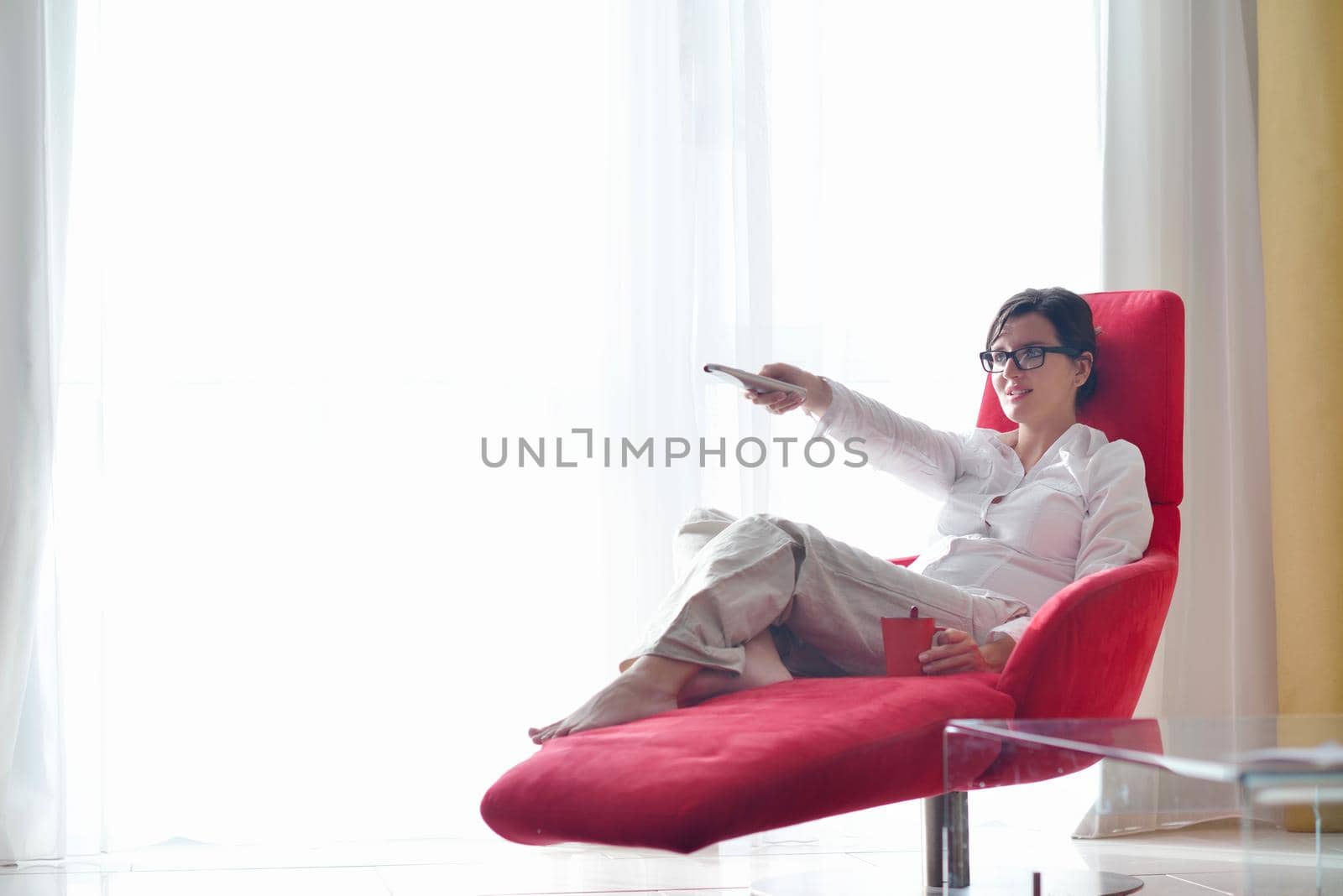 happy young woman relax at home on sofa in bright living room and watching tv