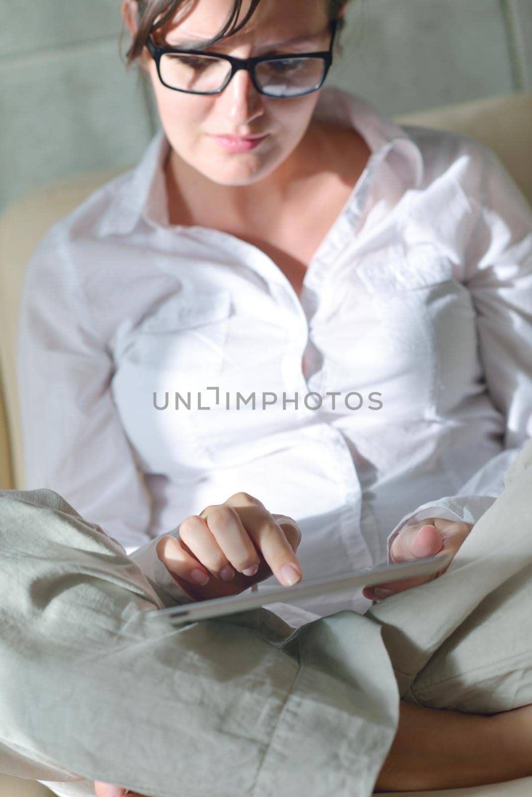 Young woman at home relaxing in her lliving room reading a digital tablet PC surf internet and work