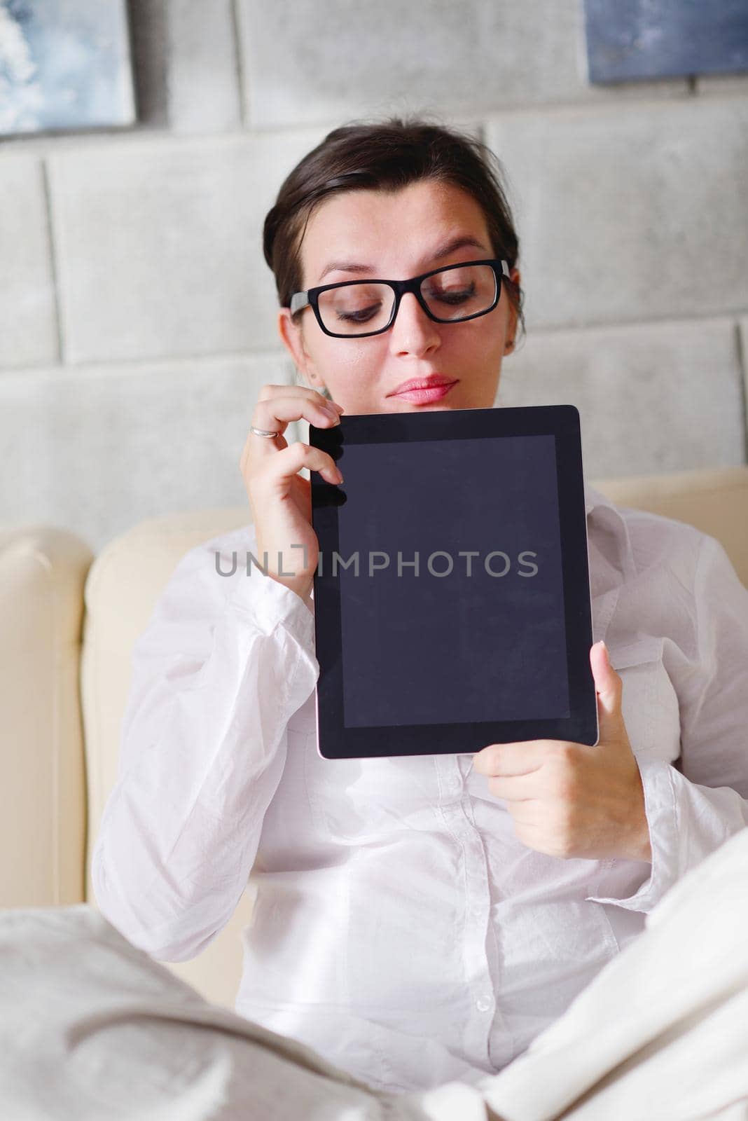 Young woman at home relaxing in her lliving room reading a digital tablet PC surf internet and work